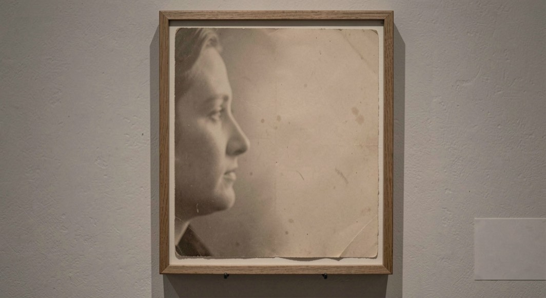 An old portrait turned partly away in a simple frame with soft paper texture and empty space